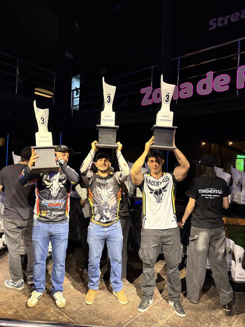 Tres pilotos levantando trofeos de tercer puesto por equipos